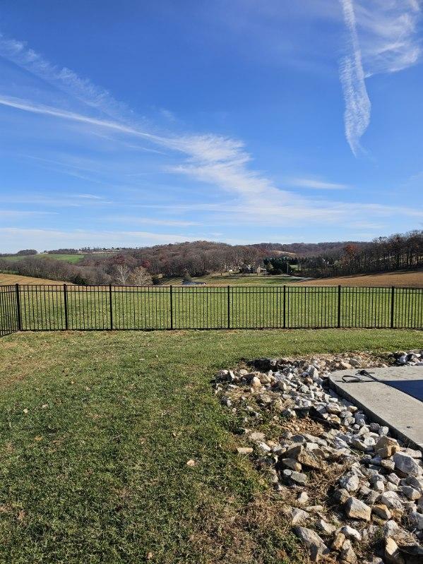 Black aluminum fence running along a planted stone bed with open ground beyond, installed by Future Solutions Fence