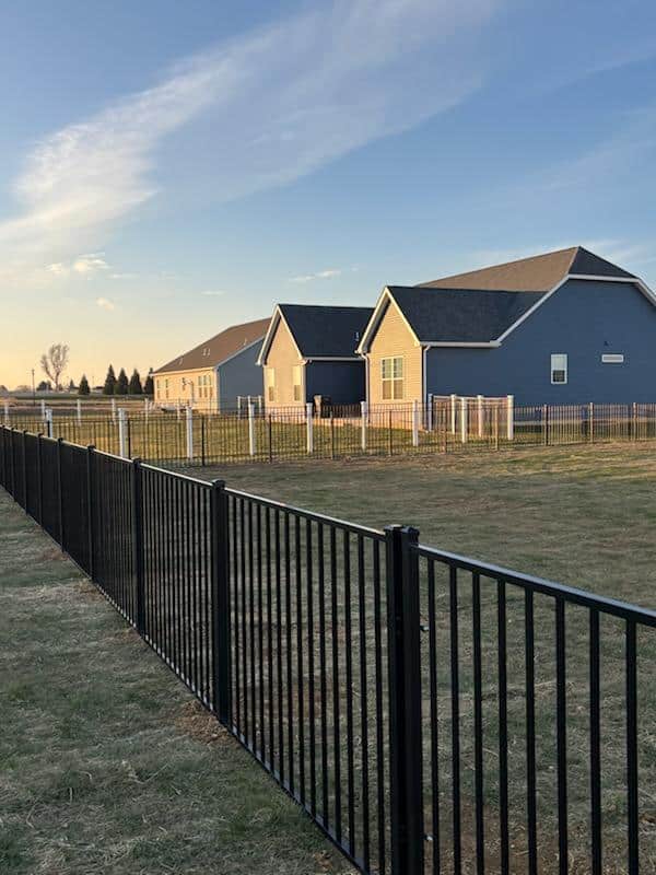 Black aluminum fence running alongside a walkway between houses, installed by Future Solutions Fence