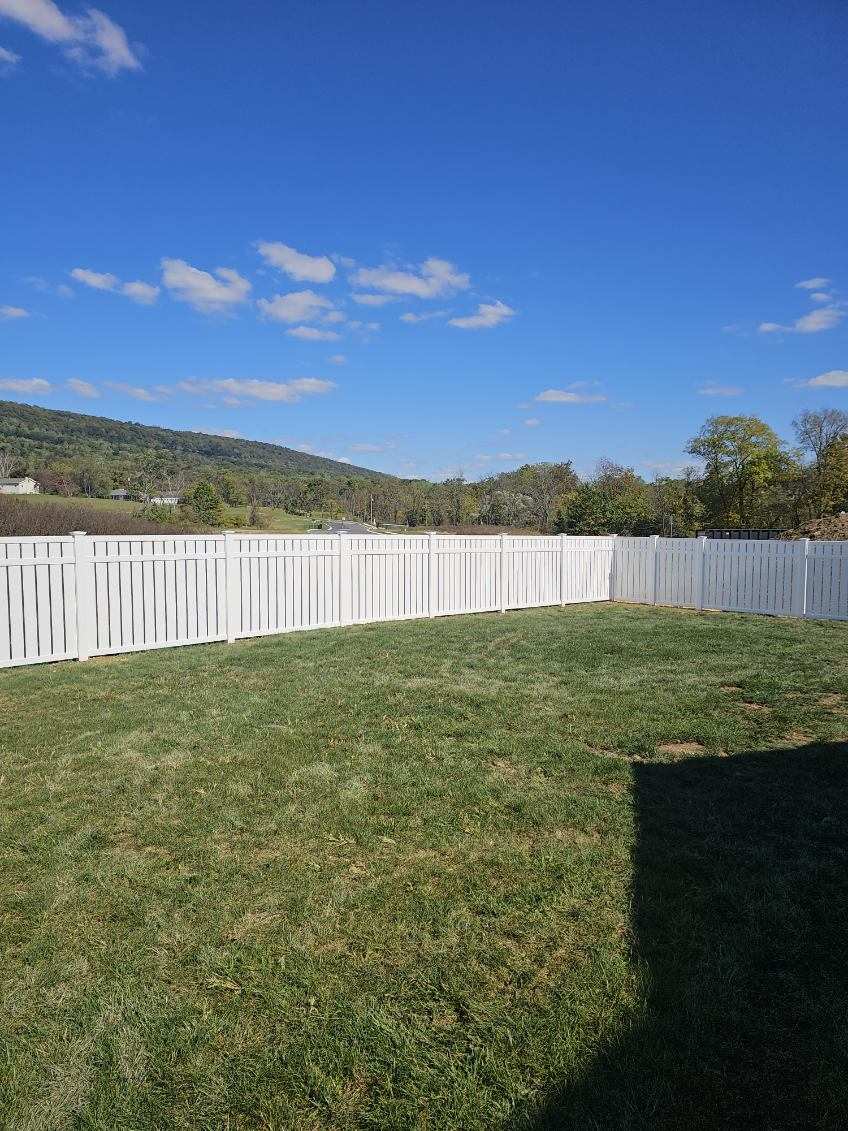 White vinyl picket fence running the length of an open lawn, installed by Future Solutions Fence