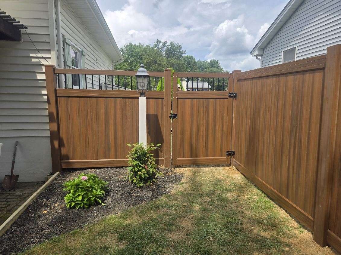 Brown vinyl fence with a gate beside a house, installed by Future Solutions Fence