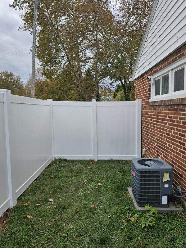 White vinyl privacy fence running beside a brick house, installed by Future Solutions Fence