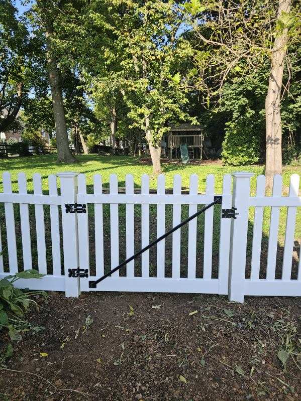 White vinyl picket fence with a walk gate under a mature tree, installed by Future Solutions Fence