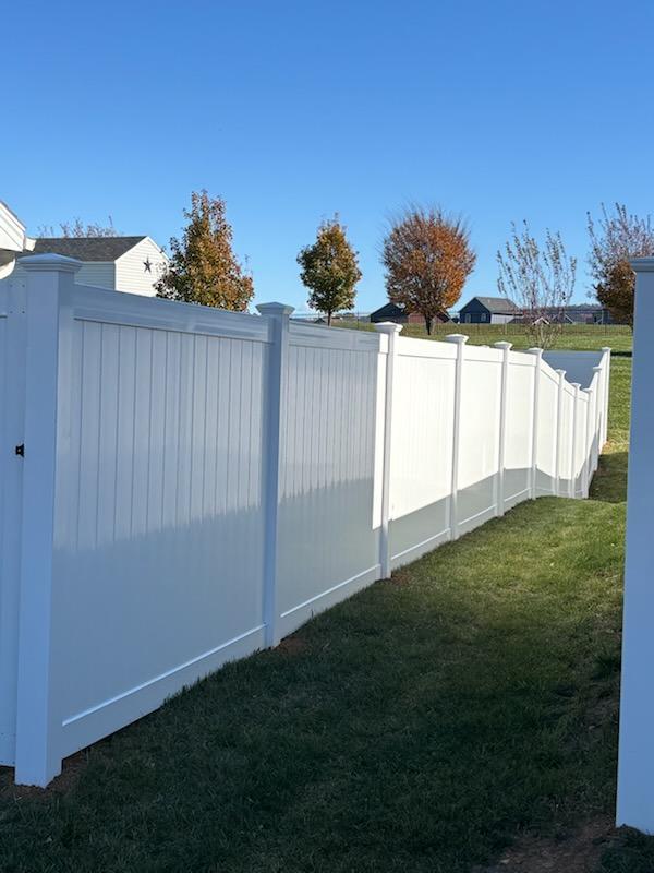White vinyl privacy fence turning a corner at the edge of a yard, installed by Future Solutions Fence