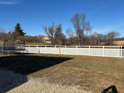 White vinyl fence running the full width of a rear yard boundary on an open lot