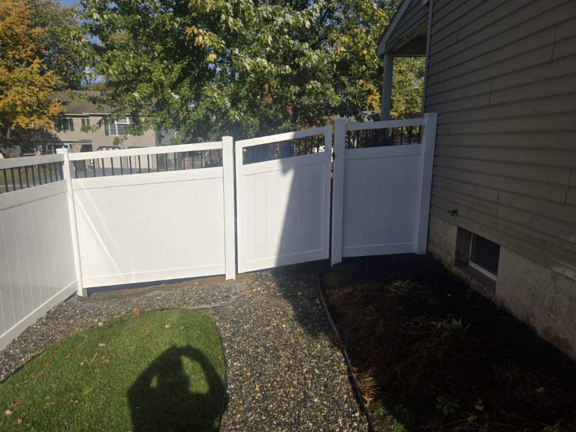 White vinyl privacy fence with a walk gate and open top section beside a house, installed by Future Solutions Fence