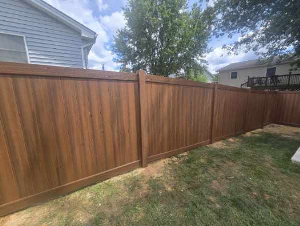 Woodgrain vinyl privacy fence enclosing a back yard, installed by Future Solutions Fence